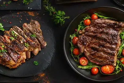 Two beautifully grilled steak platters with garnishes on a dark background.