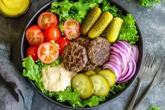 Gourmet burger bowl with sweet potato fries and fresh herbs.