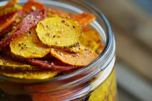 A close-up of colorful vegetable chips in a glass jar.