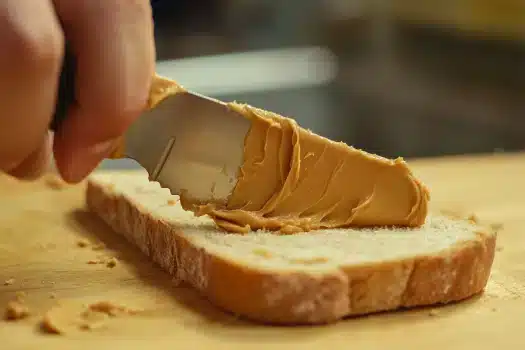 A knife spreading creamy peanut butter on a slice of bread, showing the smooth spreading action.