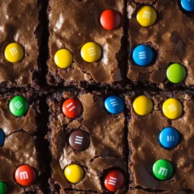 A close-up of brownies topped with colorful candy-coated chocolates arranged in a grid pattern.
