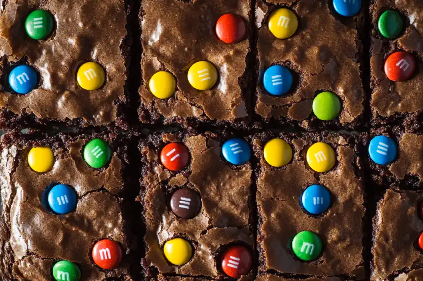 A close-up of brownies topped with colorful candy-coated chocolates arranged in a grid pattern.