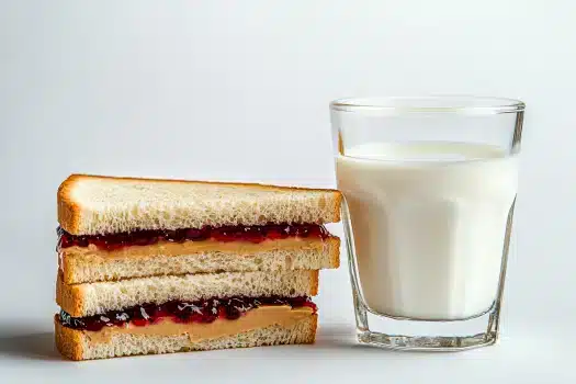 A finished and cut peanut butter and jelly sandwich, stacked neatly next to a glass of milk, on a clean background.