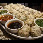 A platter of dumplings with various dipping sauces.